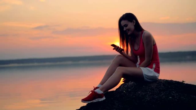一个女孩在湖边的手机上发短信。