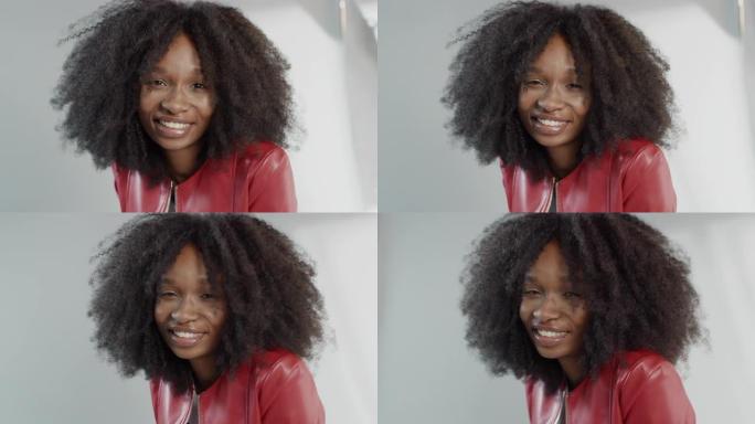 迷人的黑人女孩，郁郁葱葱的卷发摆姿势拍摄时尚杂志照片。美丽的女孩在专业工作室拍摄视频剪辑时微笑。肖像
