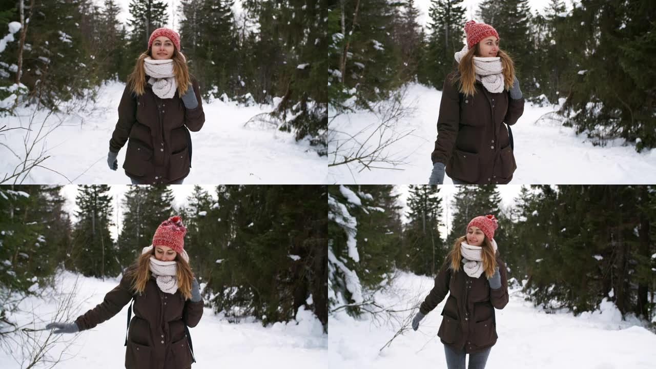 快乐的年轻女子在冬天穿过森林