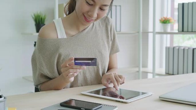 迷人的亚洲女性使用信用卡支付与数字平板电脑小工具。