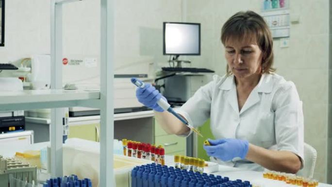 女实验室工作人员正在试管之间重新放置生物样本
