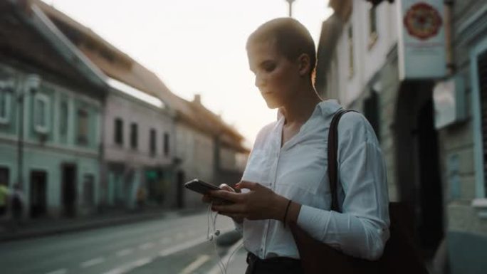 女士在黄昏时在城市使用智能手机的现代女商人