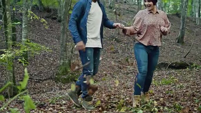多种族夫妇在森林中踢干树叶的慢动作视频