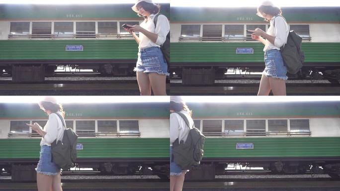 慢动作-旅行者背包客亚洲女人在泰国曼谷旅行。快乐的年轻女性使用智能手机在火车站聊天、阅读和发短信。