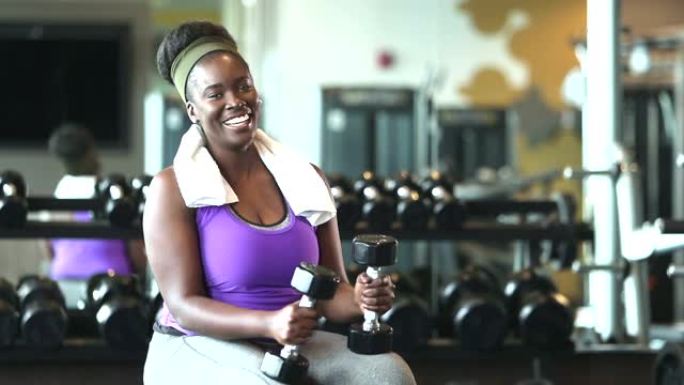 年轻的非洲裔美国妇女在健身房拿着哑铃