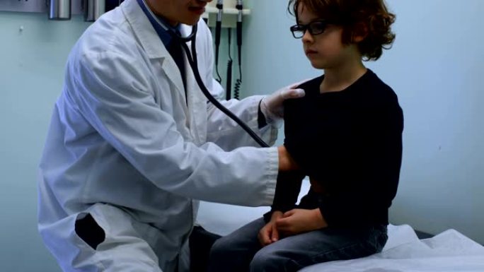 年轻的亚洲男性医生在诊所4k检查高加索男孩患者胸部的侧视图