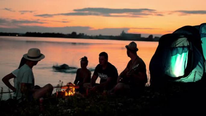 超级SLO MO一群年轻人在黄昏时在湖边露营
