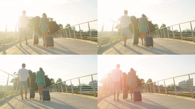 复制空间: 年轻的新婚夫妇在日落时将行李箱带到机场。