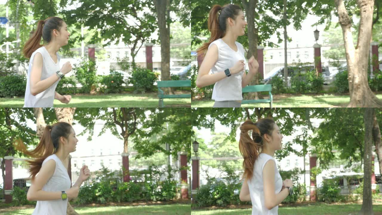 年轻迷人的女人在绿色城市公园跑步，锻炼户外健身跟踪器可穿戴技术。健身跑步运动人和健康生活方式理念。