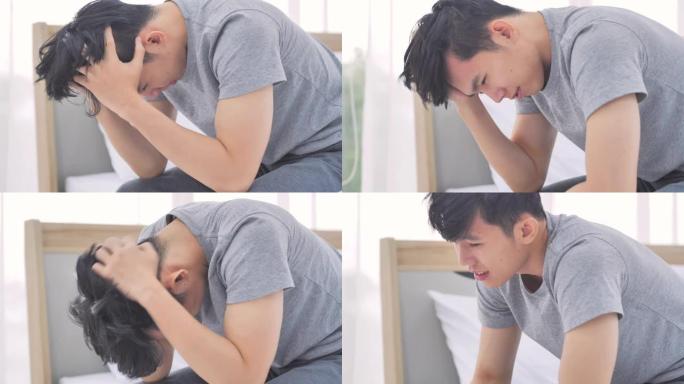 亚洲男子感到压力双手抱头感到头痛损失在家里。生病在家