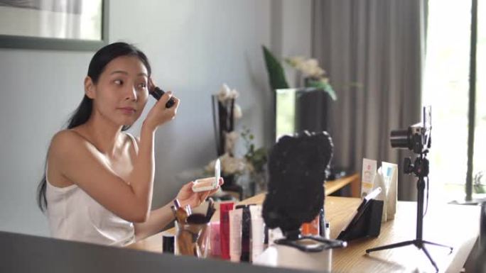 亚洲年轻女子Youtube博客在家里录制带有化妆化妆品的vlog视频，使社交媒体概念成为在线影响者。