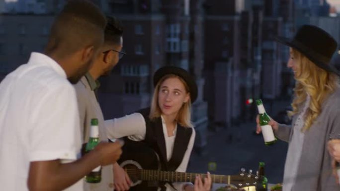 年轻女子在屋顶派对上弹吉他和朋友唱歌