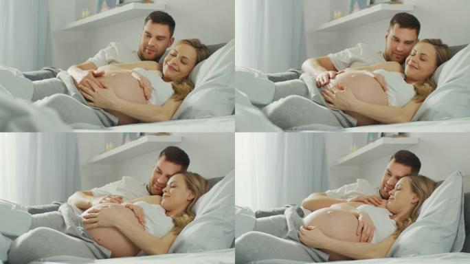 幸福的年轻夫妇在床上拥抱在一起，年轻的女人怀孕了，充满爱心的丈夫温柔地抚摸着她的肚子。相机聚焦在腹部