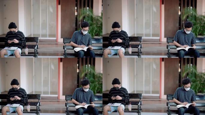 亚洲男子戴着卫生口罩，使用智能手机和阅读书籍，同时保持社交距离