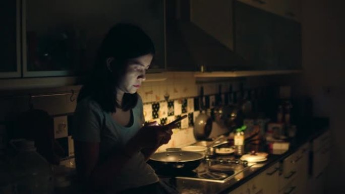 年轻的亚洲女孩坐在厨房里使用智能手机