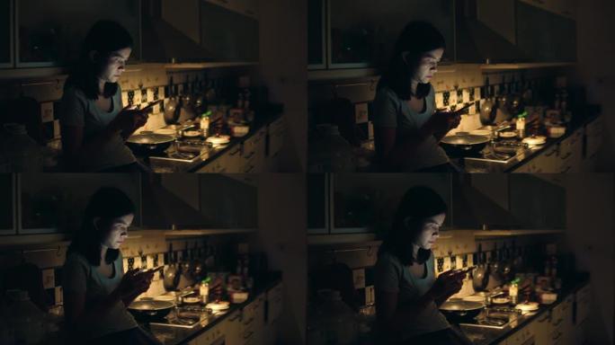 年轻的亚洲女孩坐在厨房里使用智能手机