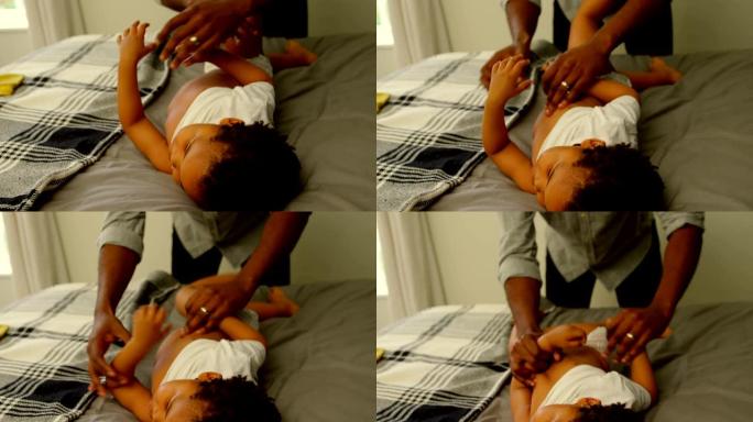 黑人父亲在舒适的家中4k帮助儿子在床上换衣服的前视图