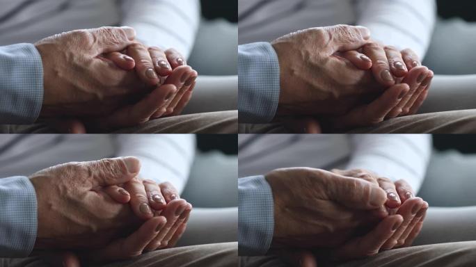 特写老年妇女拿着退休丈夫的皱纹手。