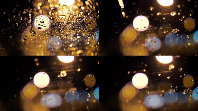 带有模糊的bokeh圆圈交通信号灯背景的汽车上的雨滴，慢动作
