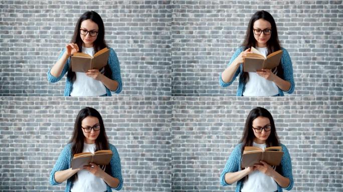 戴眼镜的严肃女孩看书翻页砖墙背景