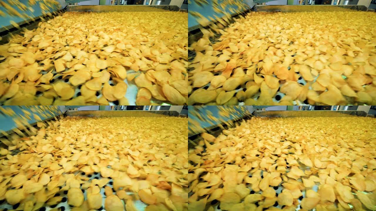 许多黄色薯片在工厂线上移动，自动化工厂设备在工作。