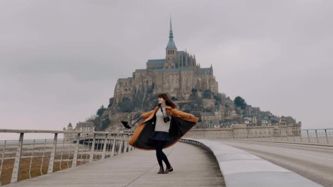 美丽快乐的自由博客作者女人张开双臂旋转，在神奇的圣米歇尔山城堡慢动作摆姿势。