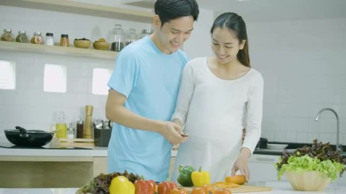 孕妇和她的丈夫在家里的厨房里一起准备健康的食物。亚洲夫妇一起做饭玩得很开心。有生活方式概念的人。