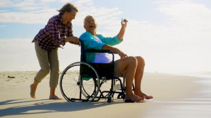 活跃的高级高加索夫妇在海滩上用手机自拍的侧视图4k