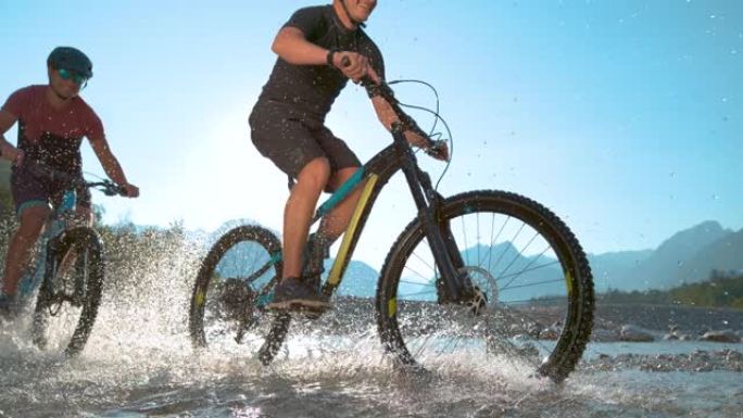 低角度: 水滴绕着两个沿河骑电动自行车的家伙飞。