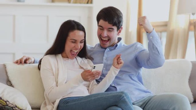 激动的夫妇在智能手机上的社交媒体上获得赠品奖