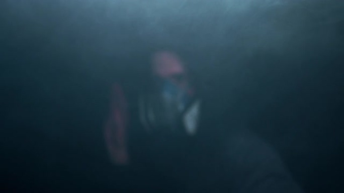 在黑暗的背景上，一个戴着面具的男人在周围的烟雾中跳舞。