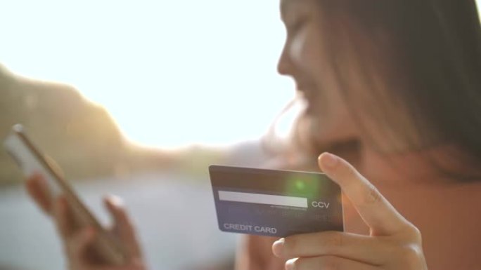 快乐的亚洲女人用信用卡用智能手机在线购物