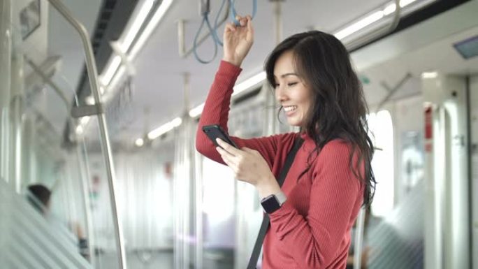 年轻的亚洲女性在地铁的公共交通中使用智能手机