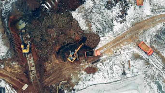 挖掘机和卡车工作的建筑工地上方的鸟瞰图。