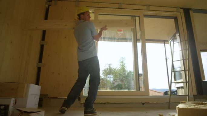 低角度: 承包商拿起一块木板，将其穿过CLT房屋。