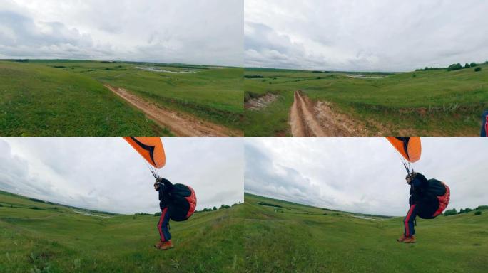 一个人加速驾驶滑翔伞飞越田野。
