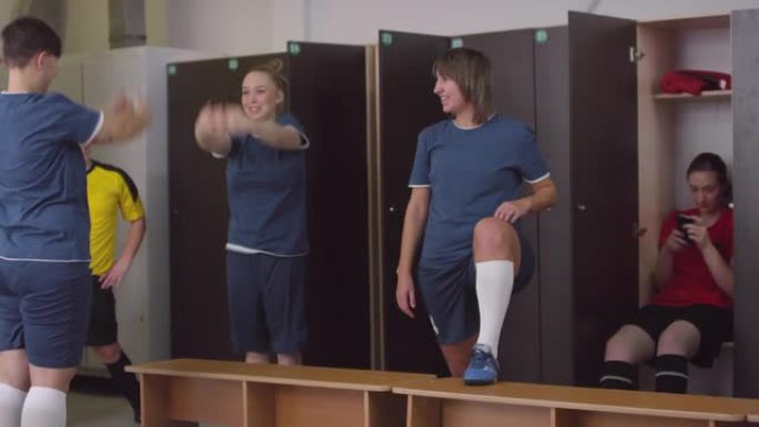 开朗的女足球运动员在更衣室里热身