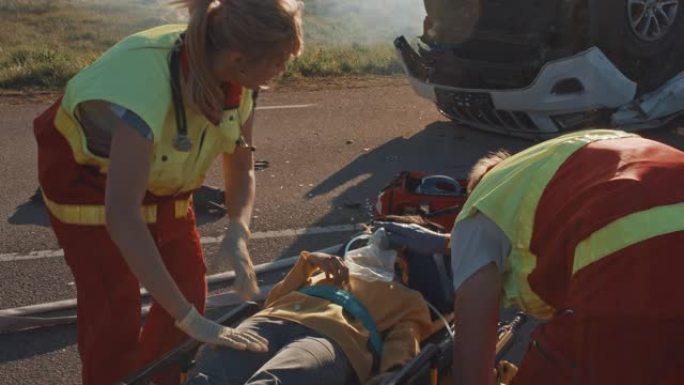 在车祸交通事故现场: 医护人员挽救了一个躺在担架上的小女孩的生命，她得到了最好的急救帮助。专业医务人