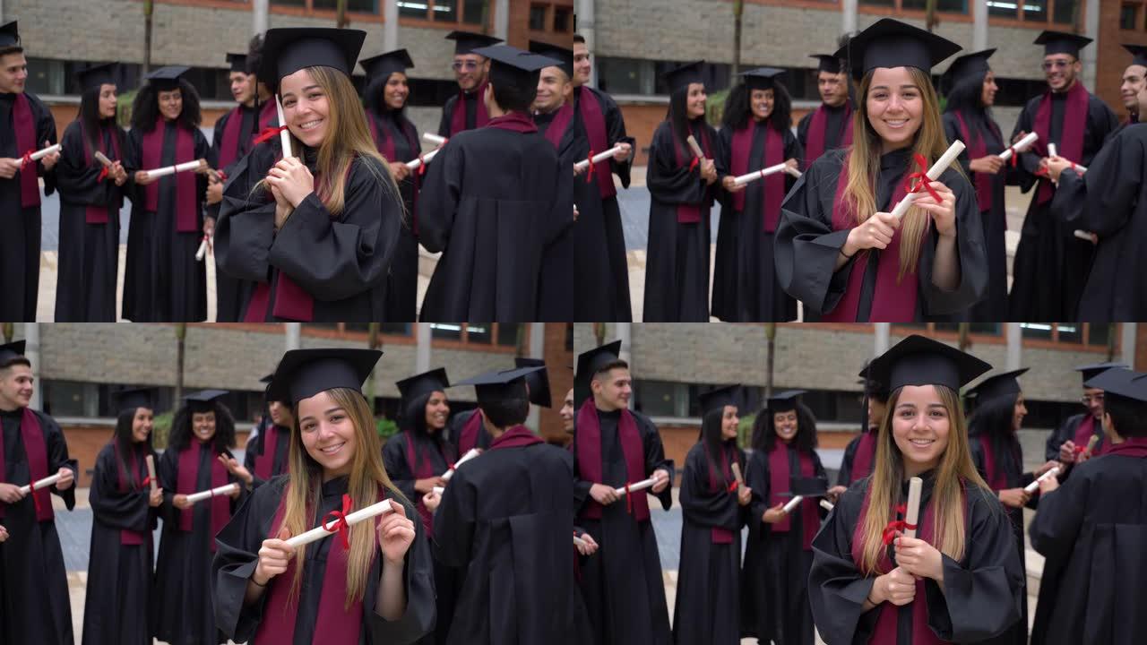 美丽的女学生拿着文凭兴高采烈地看着相机，而朋友们则在后台庆祝