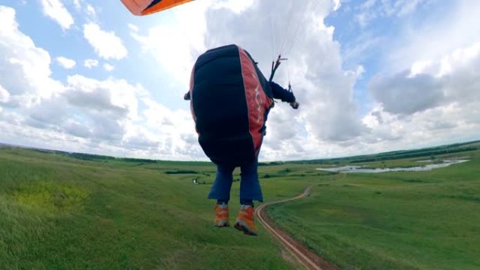 一个人驾驶滑翔伞飞过田野。