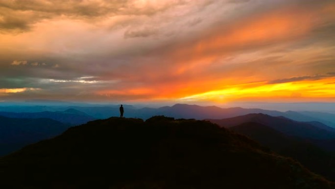 站在山上的男人在美丽的夕阳下