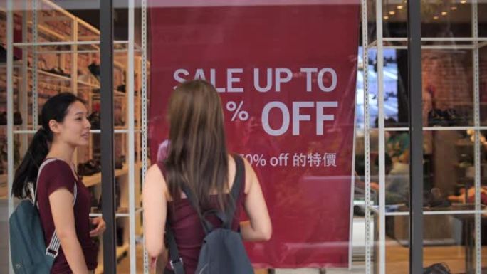 两名亚洲妇女一起聊天，看着零售展示