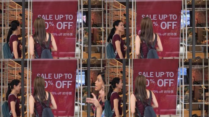 两名亚洲妇女一起聊天，看着零售展示