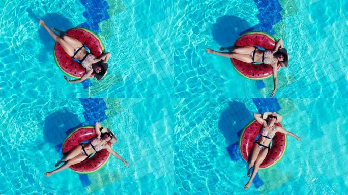 年轻女子躺在旅馆游泳池的橡胶圈上。