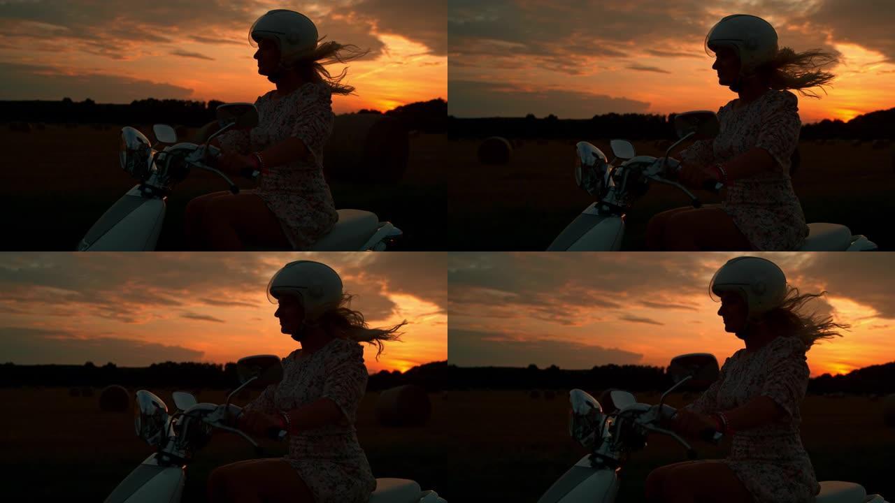 日落时骑踏板车的超级SLO MO女人