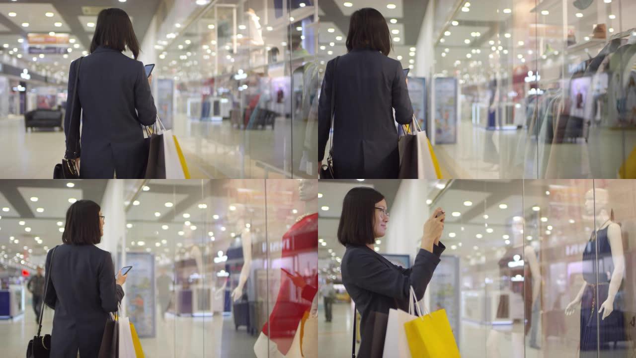 年轻的亚洲妇女在商店橱窗里为人体模特拍照