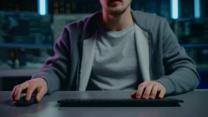 匿名软件开发人员/黑客坐在办公桌前，在数字身份网络安全数据中心的计算机上工作。黑客攻击或编程。视点相