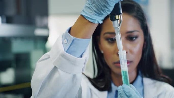 深色皮肤的肖像女科学家正在分析一种液体，以提取实验室试管中的DNA和分子