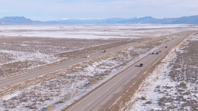 航拍图:在沥青高速公路上飞行，引领车辆穿越白雪皑皑的沙漠