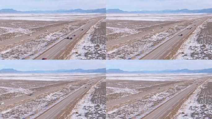 航拍图:在沥青高速公路上飞行，引领车辆穿越白雪皑皑的沙漠